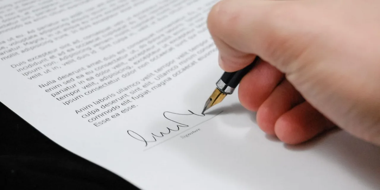 Close-up of a hand signing a legal document with a fountain pen, symbolizing signature and agreement.